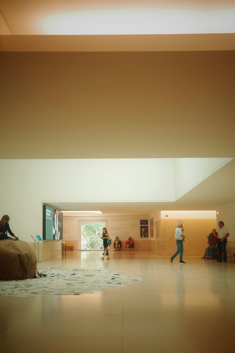 Visitatori esplorano una galleria d'arte moderna con un grande schermo.