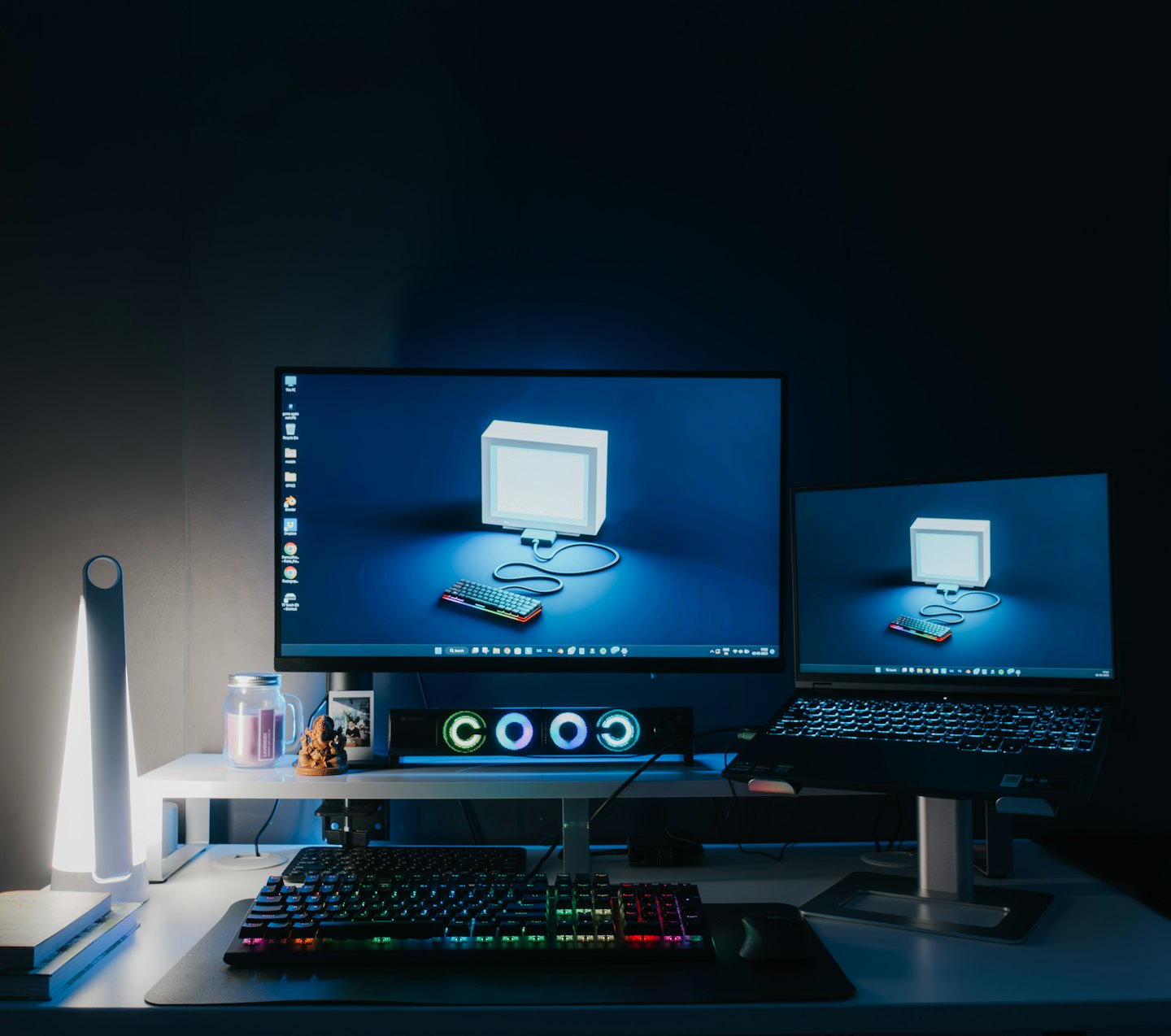 Postazione di lavoro con doppio monitor e laptop che visualizzano un'immagine 3D.